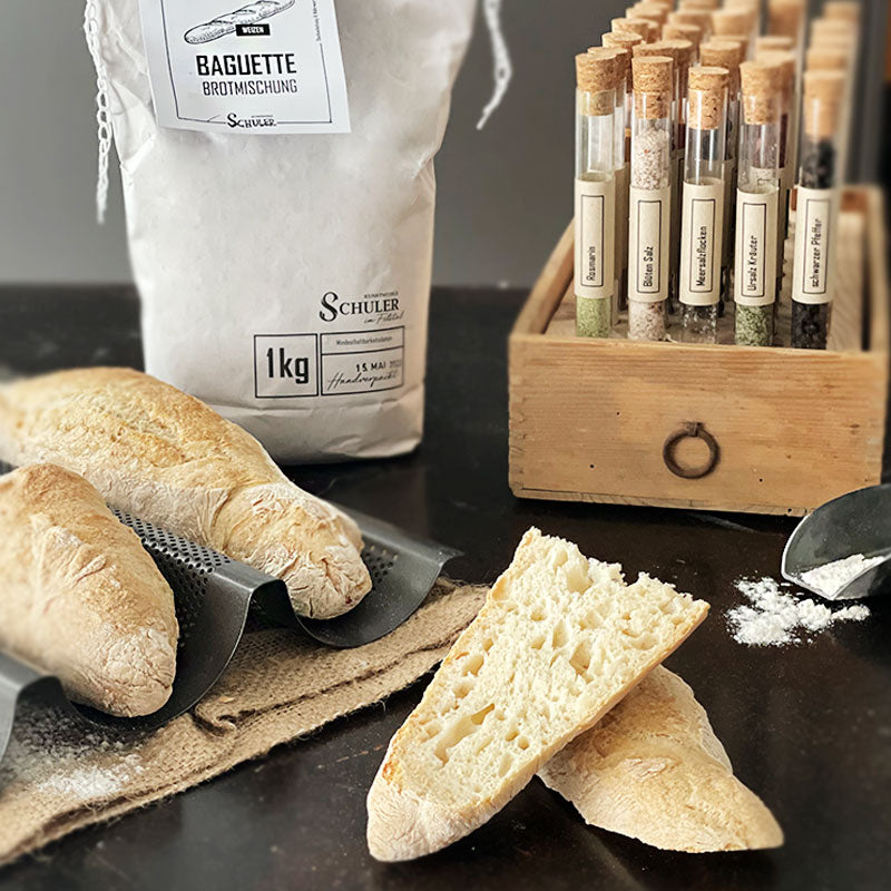 Die Mehlbackmischung Baguette hinter einem aufgeschnittenen Baguette mit toller Porung und Lufteinschüssen