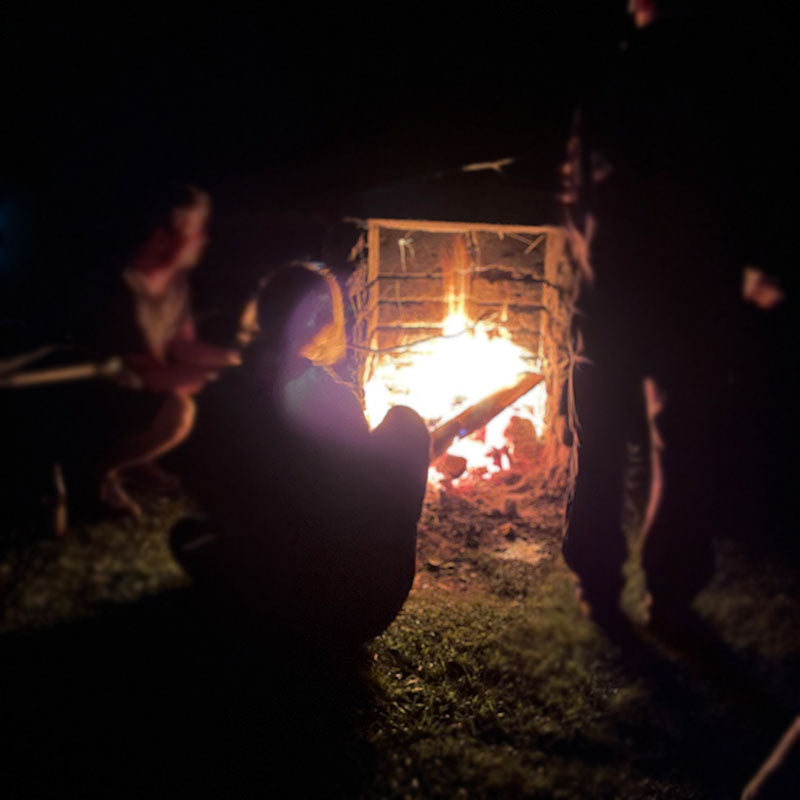 Mehrere Personen am gemütlichen Lagerfeuer mit Stockbrot