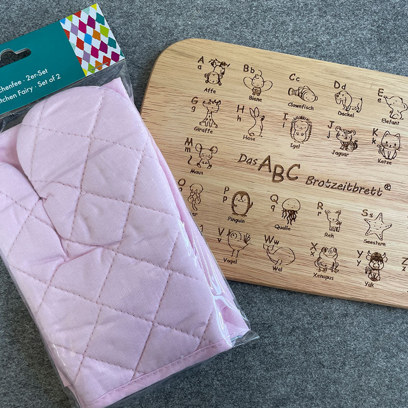 Breitzeitbrett ABC, hierauf werden mit Hilfe vom Tieren die Buchstaben gezeigt und das Kinderschürzen und -handschuhe Set der Firma Städter in der Farbe Rosa