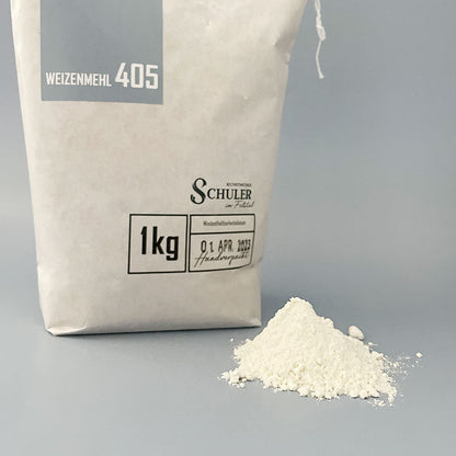 Ein weißer Mehlhaufen der Mehltype 405 samt Verpackung des Backshops Mehl und Mehr